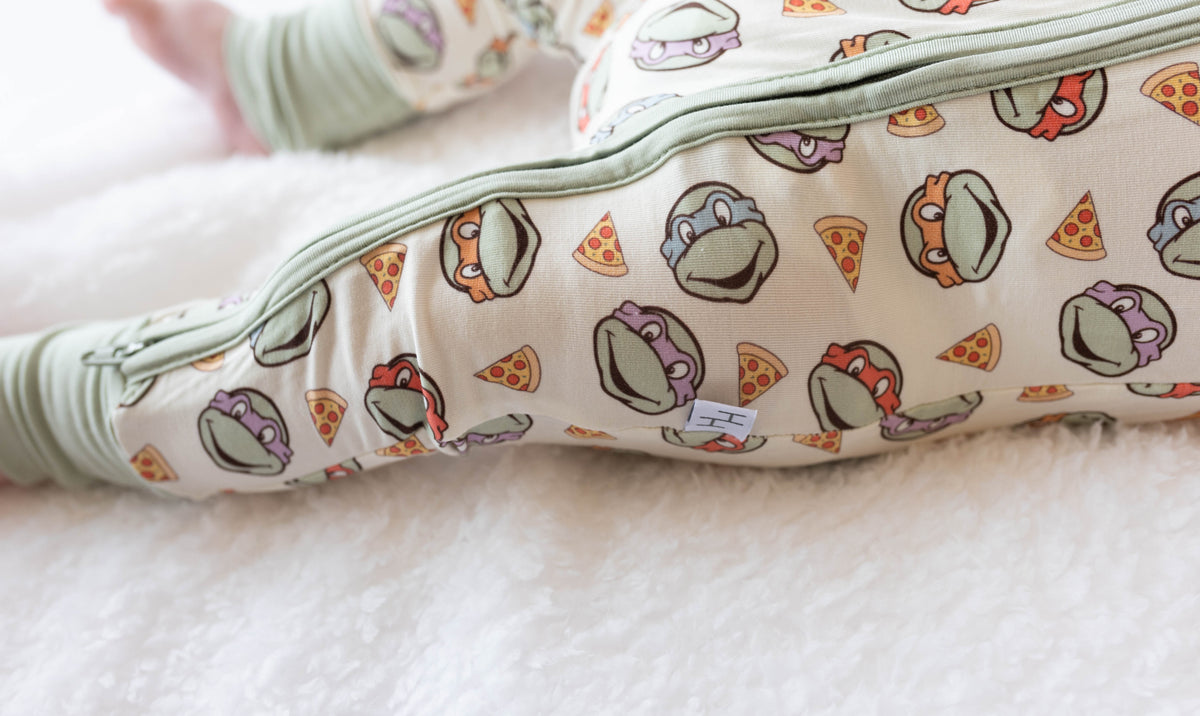 Close-up of soft bamboo fabric texture and repeating turtle pizza pattern on baby sleeper
