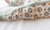 Close-up of soft bamboo fabric texture and repeating turtle pizza pattern on baby sleeper