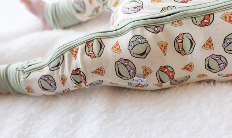 Close-up of soft bamboo fabric texture and repeating turtle pizza pattern on baby sleeper