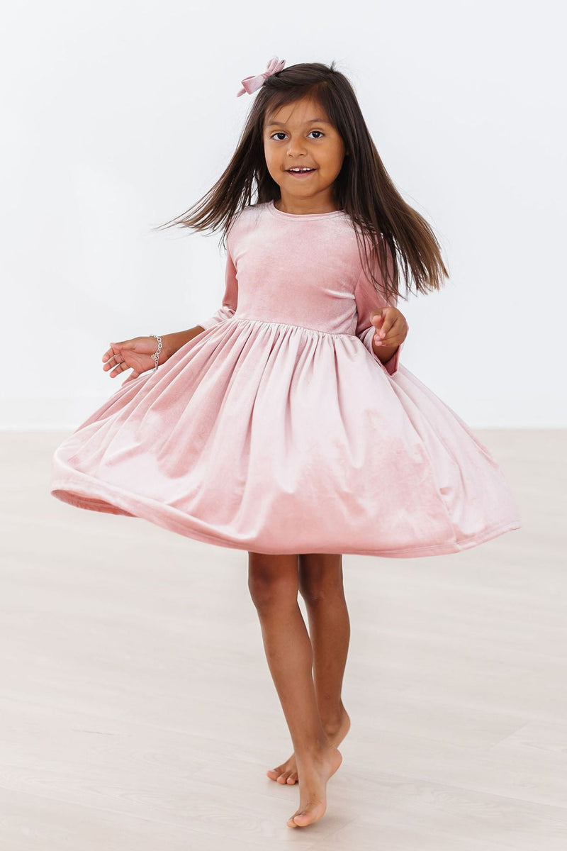 Young girl joyfully spinning in a Vintage Pink Velvet Twirl Dress, demonstrating the dress's twirl effect and playful nature.