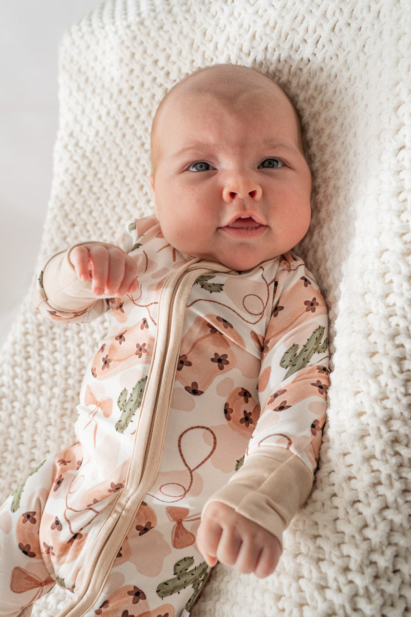 Close-up of beige zipper guard and soft bamboo fabric texture on cowgirl print onesie