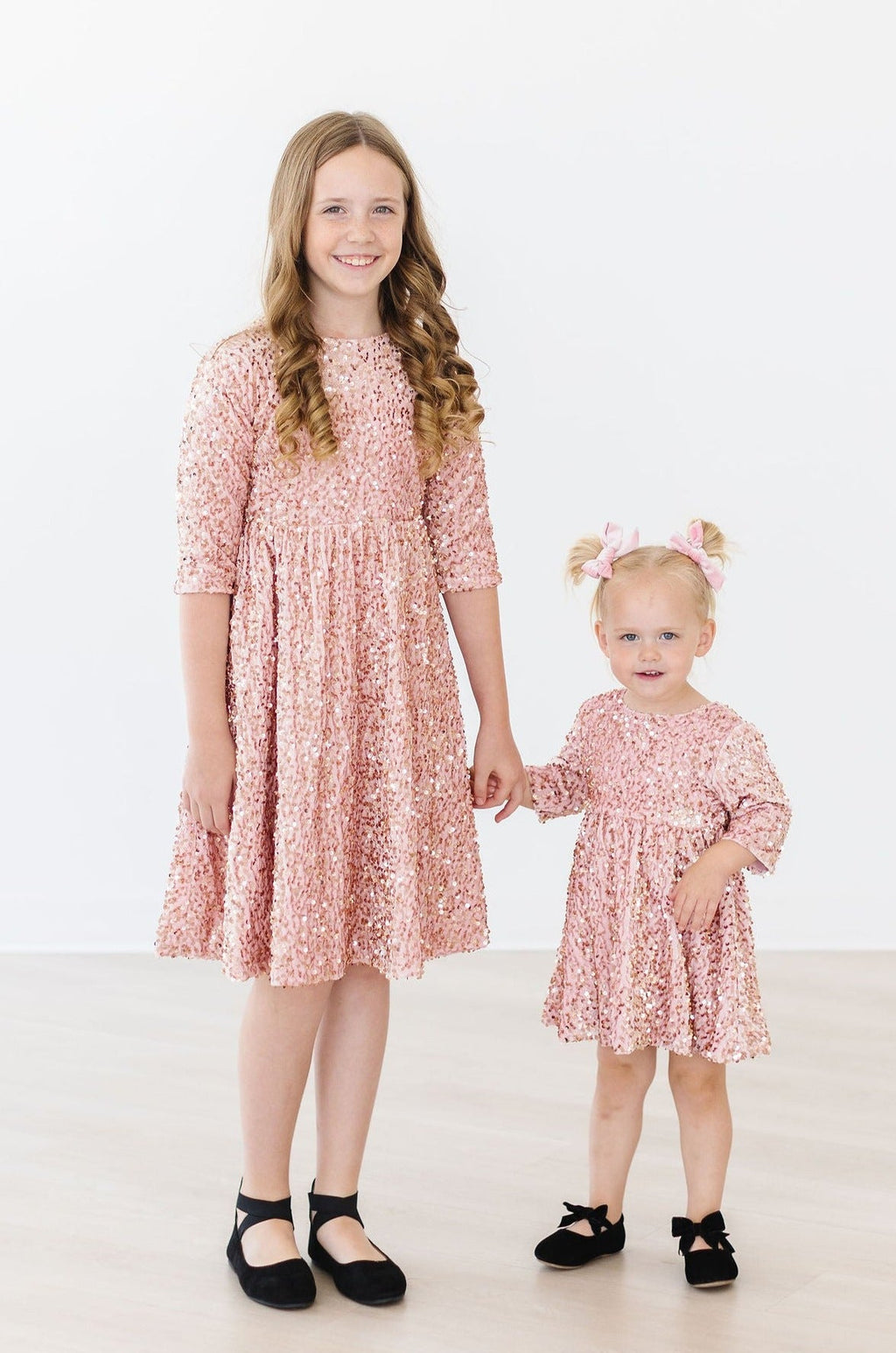 Two girls wearing Rose Gold Velvet Sequin Dresses from Mila & Rose, showcasing the sparkling design and elegant color, perfect for special occasions.