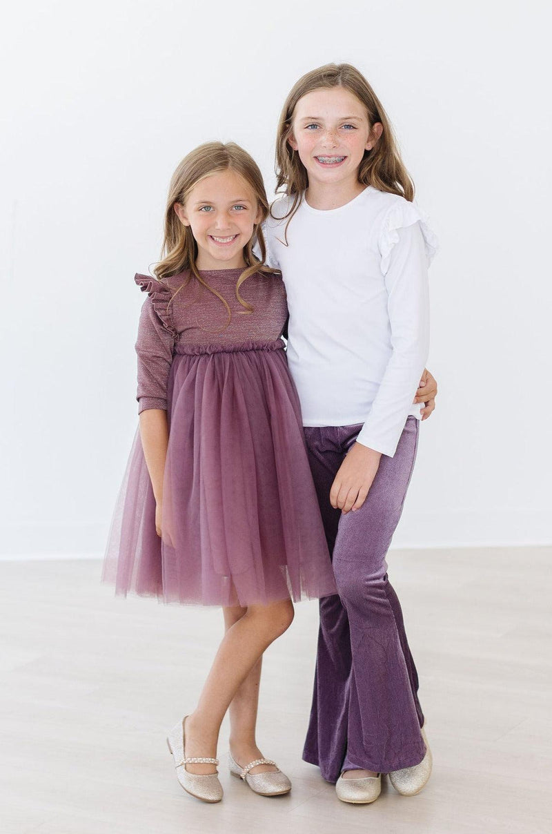 Two stylish girls showcasing the Amethyst Ribbed Velvet Bells alongside a matching amethyst dress, perfect for a fashionable day out or family photos.