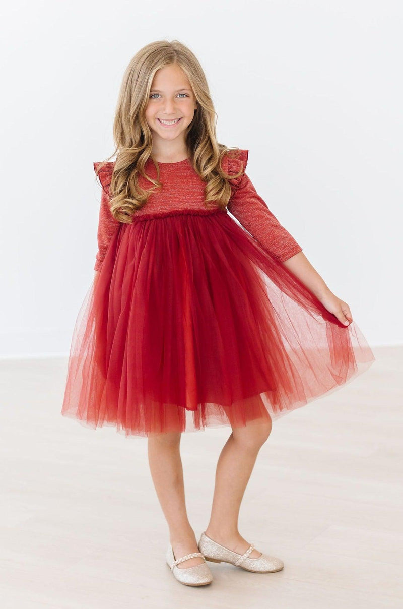 Cheerful girl gracefully posing in a Pumpkin Spice Shimmer 3/4 Sleeve Tutu Dress with her hands on the skirt.