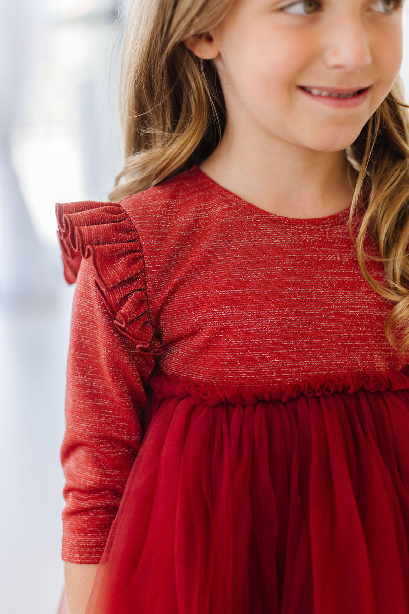 Close-up of a girl in a Pumpkin Spice Shimmer 3/4 Sleeve Tutu Dress highlighting the ruffled shoulders and soft fabric.