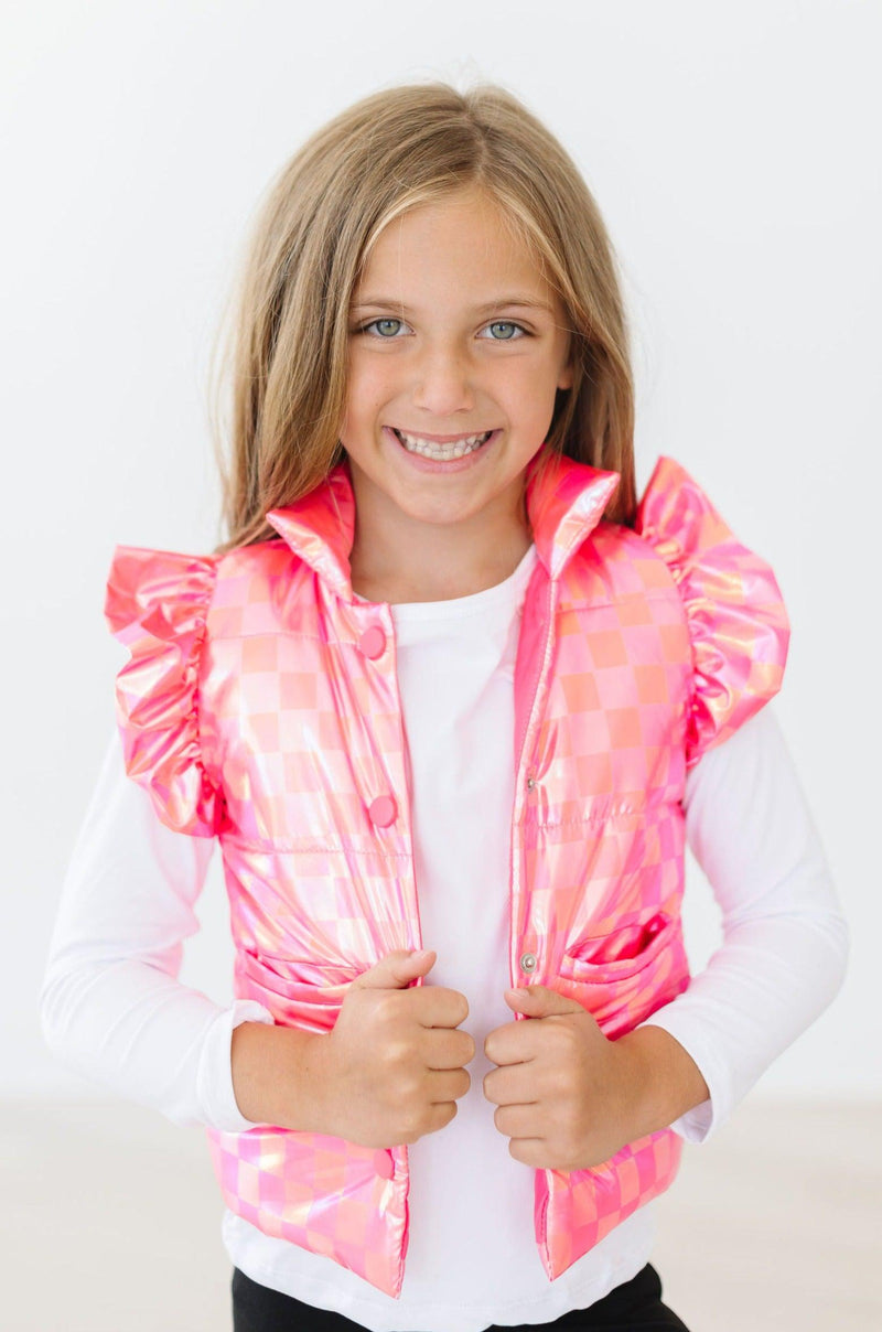 A delighted girl poses in the Neon Pink Checker Puffer Vest, emphasizing the eye-catching neon pink pattern and stylish ruffles, making it a fashionable winter staple.