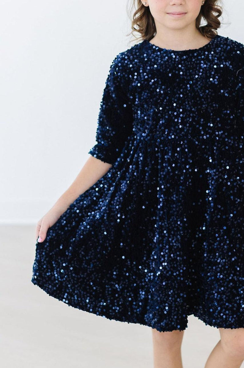 Close-up of a young girl wearing the Navy Velvet Sequin Dress by Mila & Rose®, highlighting the shimmering sequins and luxurious velvet material.
