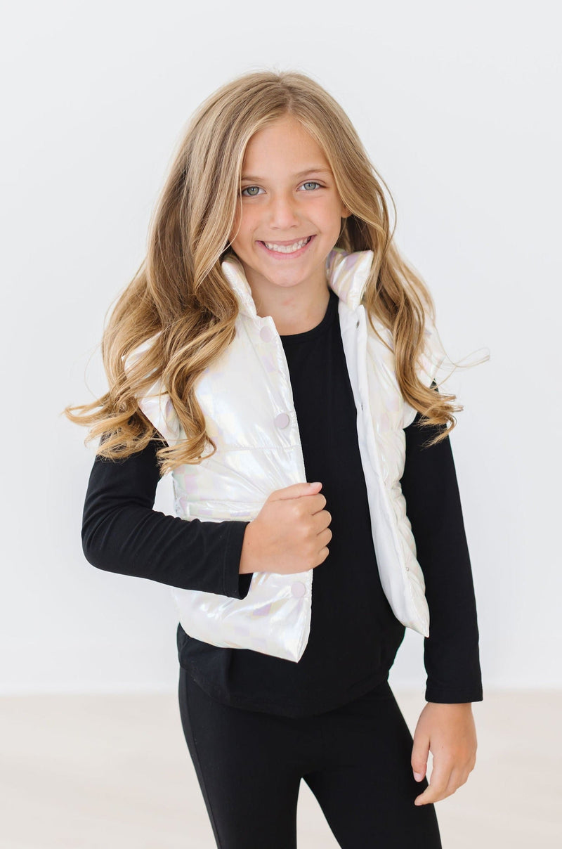 Happy girl showing off the White Checker Puffer Vest by Mila & Rose, styled with a black outfit for a chic winter ensemble.