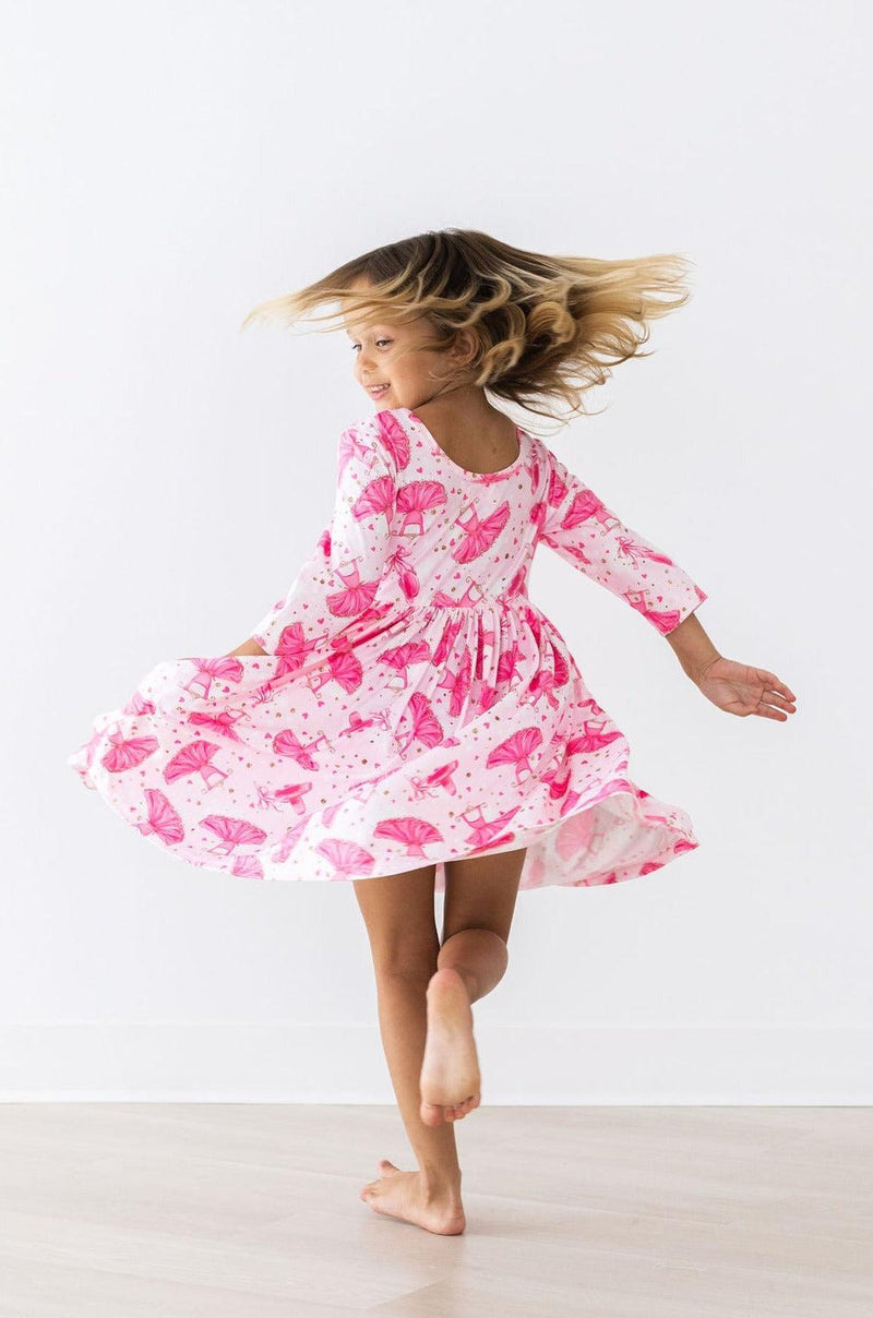 A joyful girl dancing in the Pirouette 3/4 Sleeve Pocket Twirl Dress, showcasing its full skirt and playful design. Perfect for twirling!