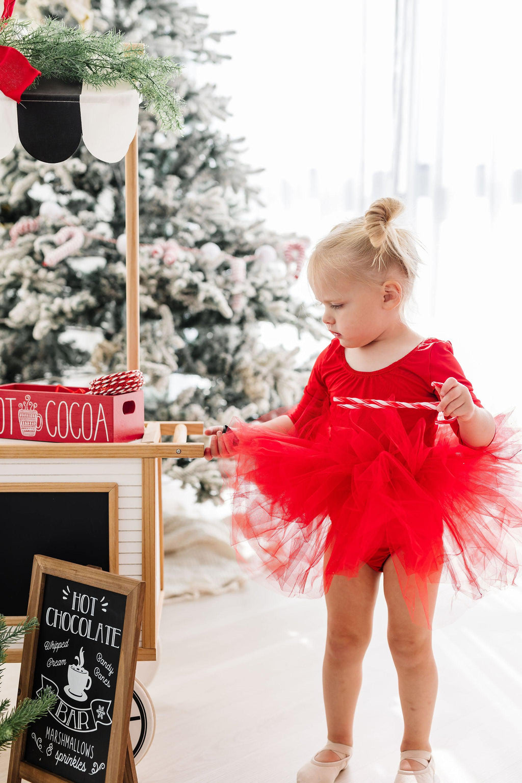 A young girl happily playing with a toy while wearing a Festive Red 3/4 Holiday Fluffy Tutu Leotard for Girls, showcasing the enchanting fullness of the tutu design, perfect for dance classes and festive celebrations.
