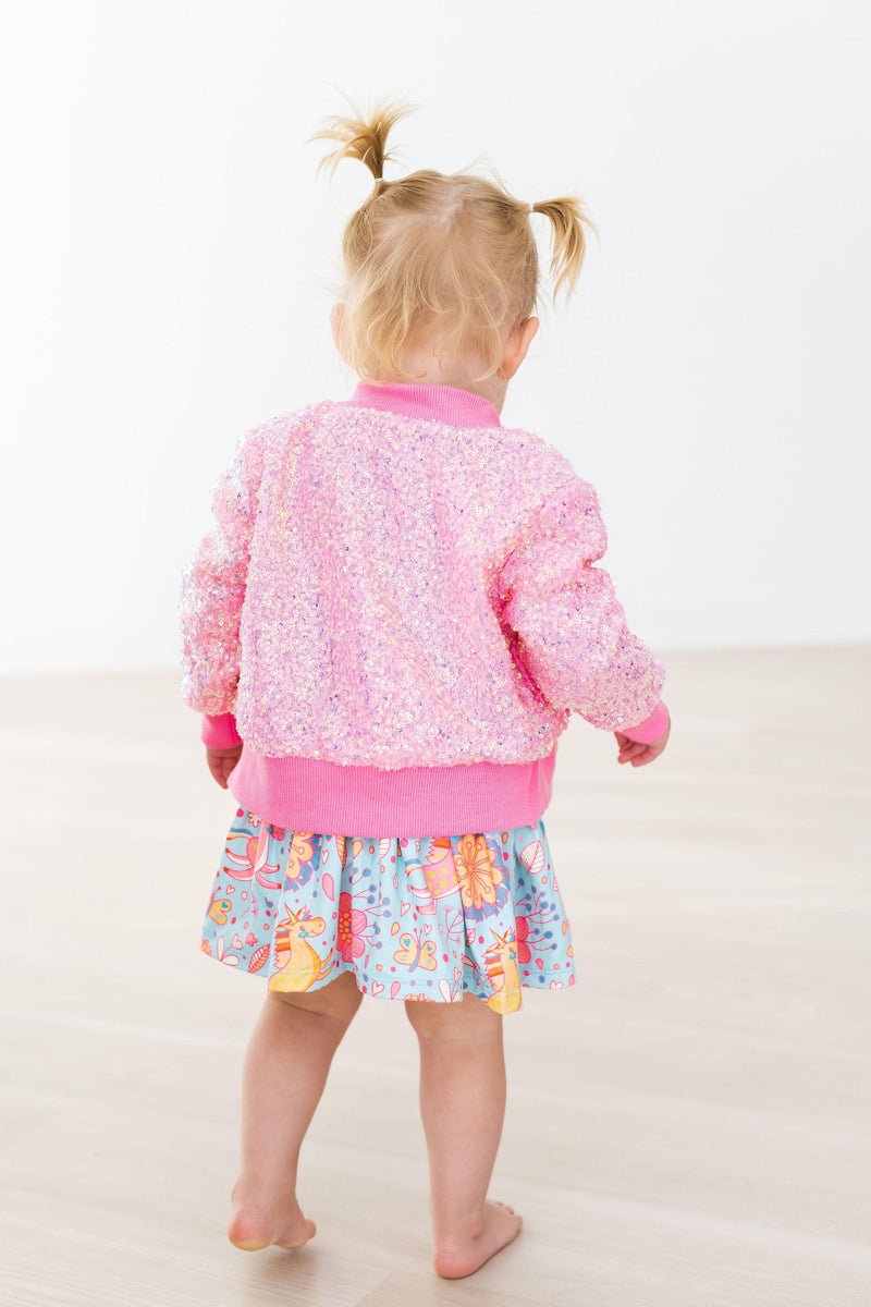 Child seen from the back wearing a Bubblegum Pink Sequin Jacket, paired with a colorful skirt, exuding playful fashion.