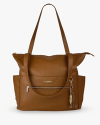 Cognac pebbled vegan leather diaper bag front view with gold zippered pocket, feather tassel charm, and open side pockets
