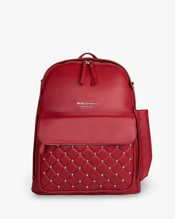 Crimson vegan leather Daphne diaper bag featuring gold studs, quilted front pocket, and coastal-inspired luxury design for style and utility.