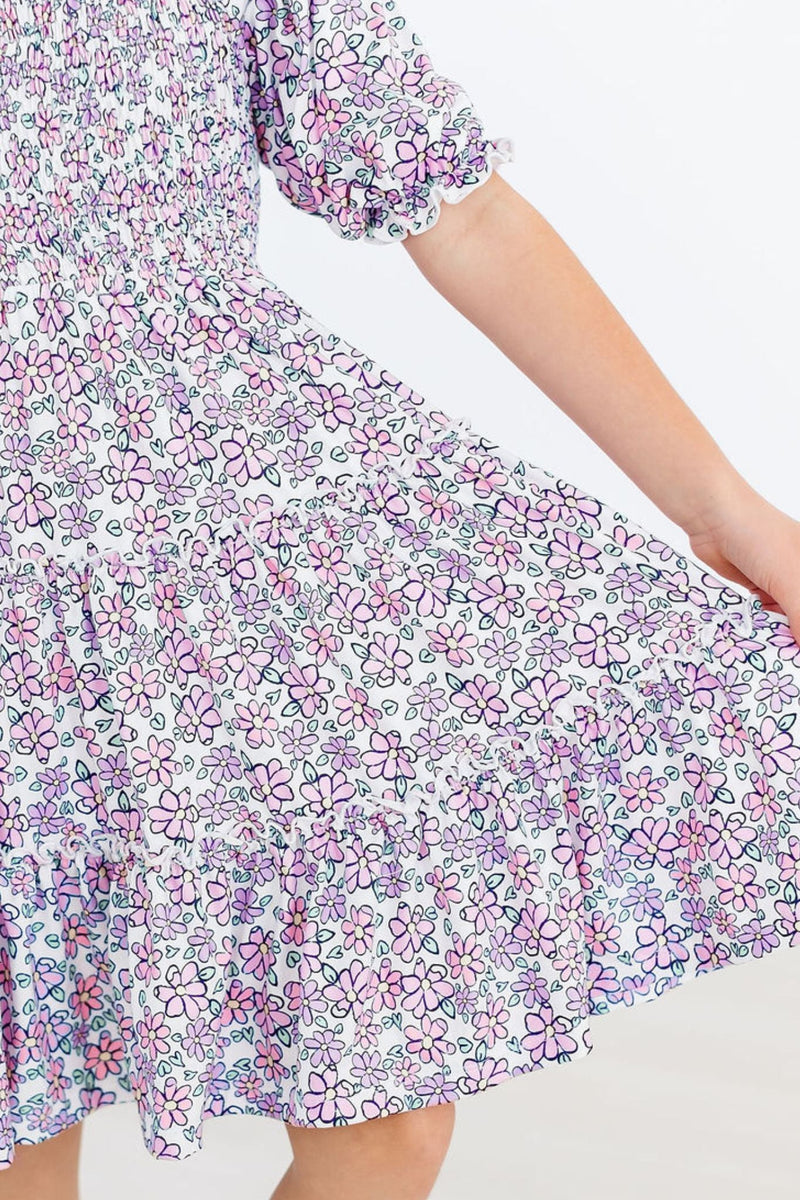 Detail shot of the striking floral pattern and ruffled hem of the Lovely Lavender Smocked Ruffle Dress, a perfect blend of play and elegance.
