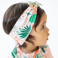 SoftKnot Bow Desert Cactus beige bamboo head-wrap with cactus print on a baby's head.