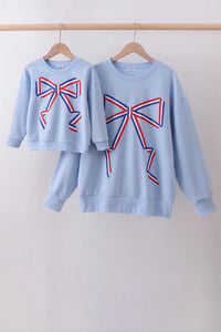 Two light blue sweatshirts with red and blue bow designs on a white background.