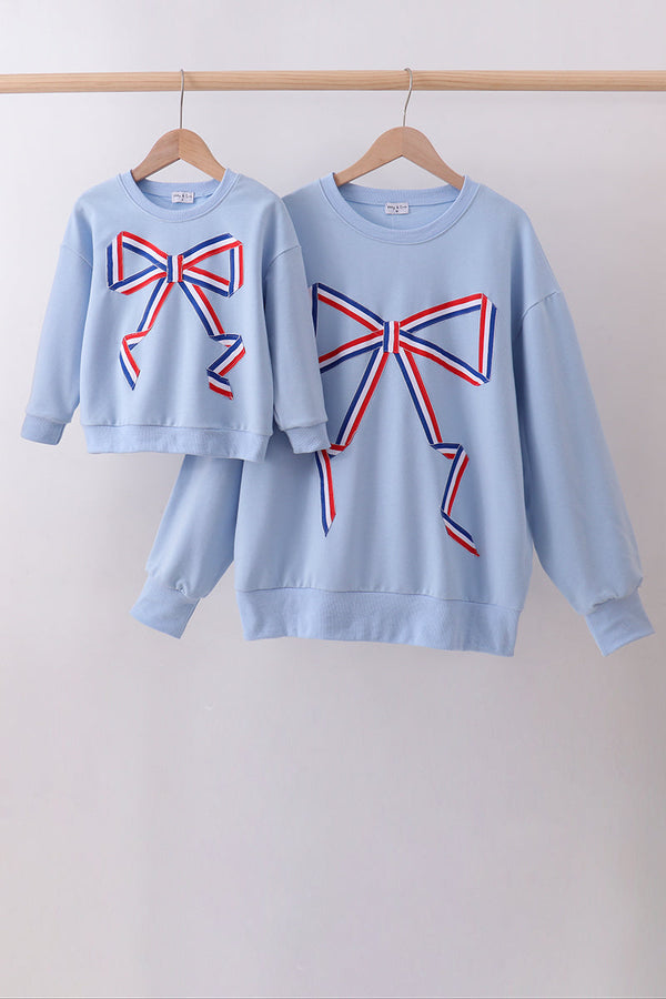 Two light blue sweatshirts with red and blue bow designs on a white background.