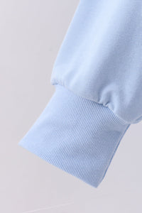 Close-up of a light blue sweater sleeve on a neutral background