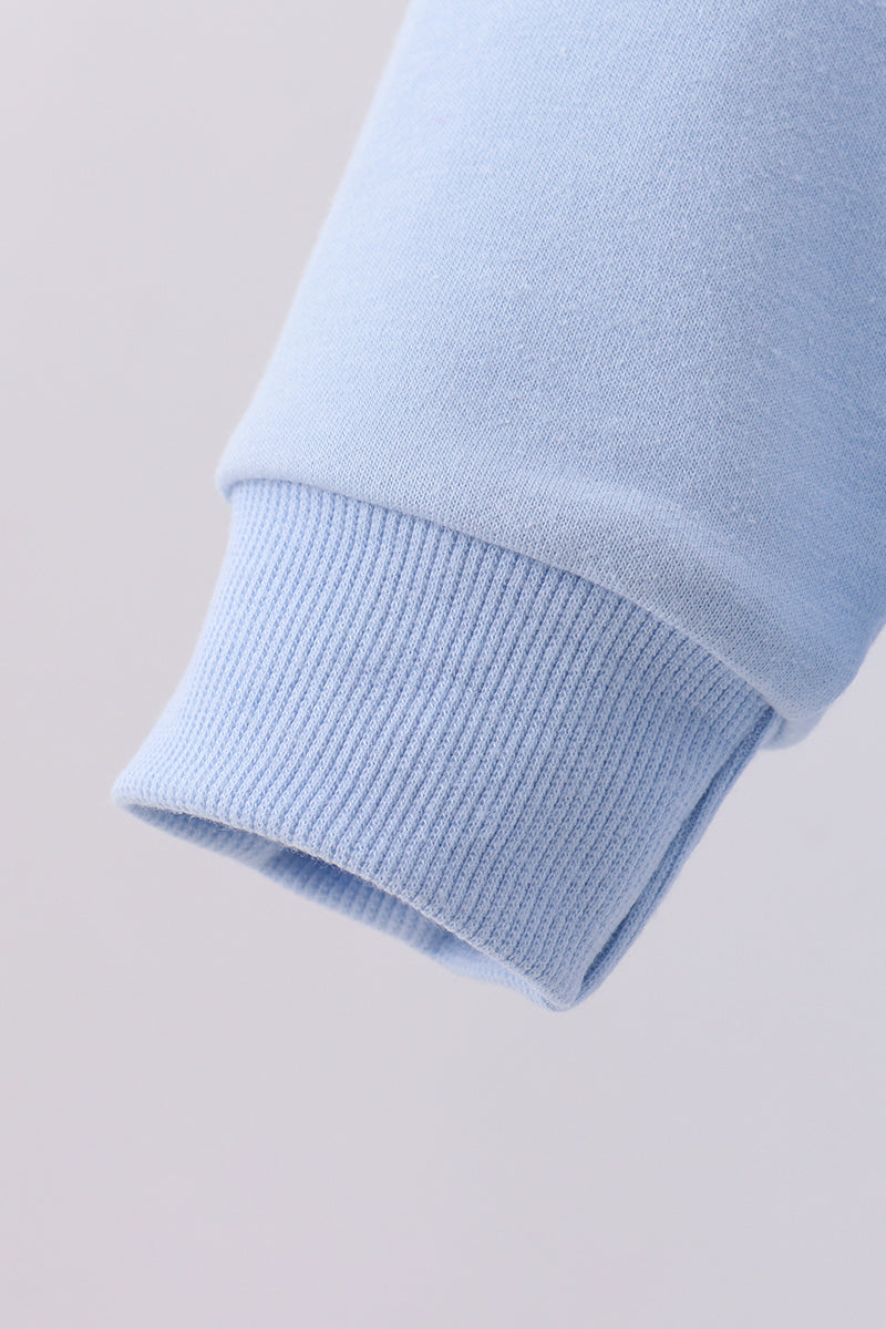 Close-up of a light blue sweater sleeve on a light gray background
