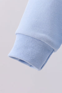 Close-up of a light blue sweater sleeve on a light gray background