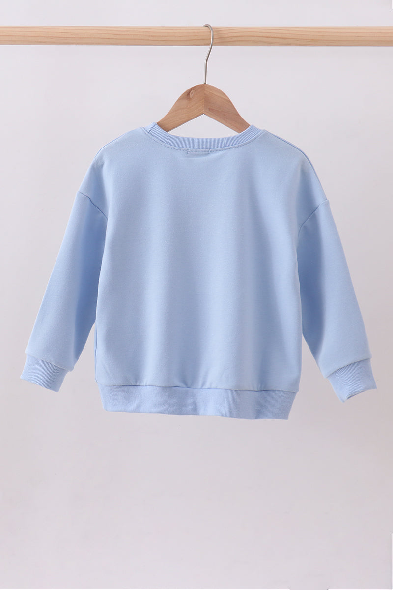 Light blue sweatshirt on a wooden hanger against a plain background