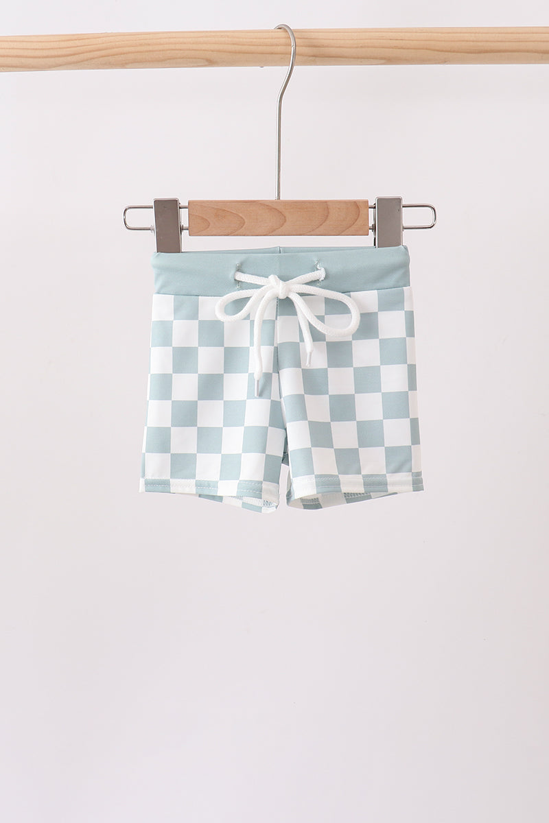 Checkered shorts with a tie waist hanging on a wooden hanger against a white background