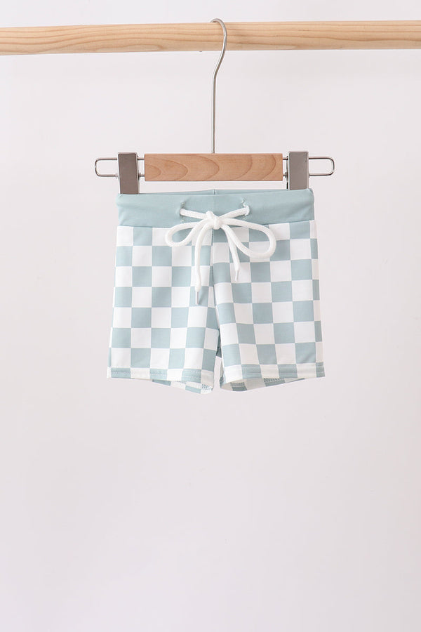 Checkered shorts with a tie waist hanging on a wooden hanger against a white background
