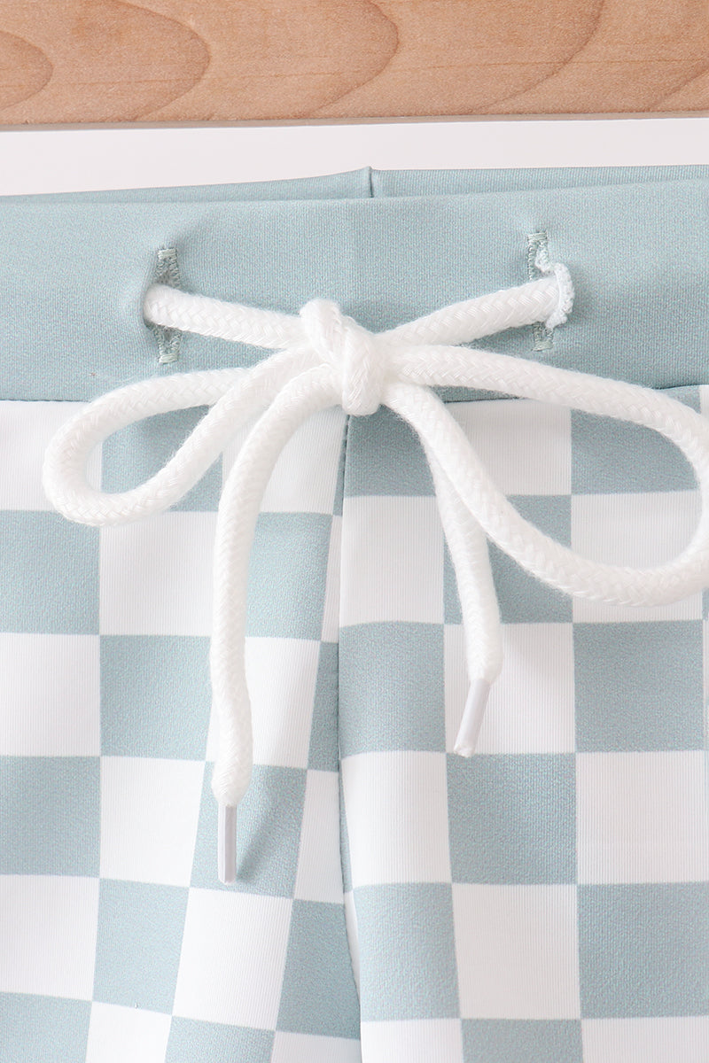 Checkered curtain with white tieback on a light blue and white checkered fabric background.