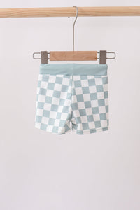 Checkered shorts hanging on a wooden hanger against a white background