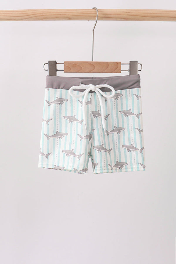 Children's shorts with shark pattern on a hanger against a white background
