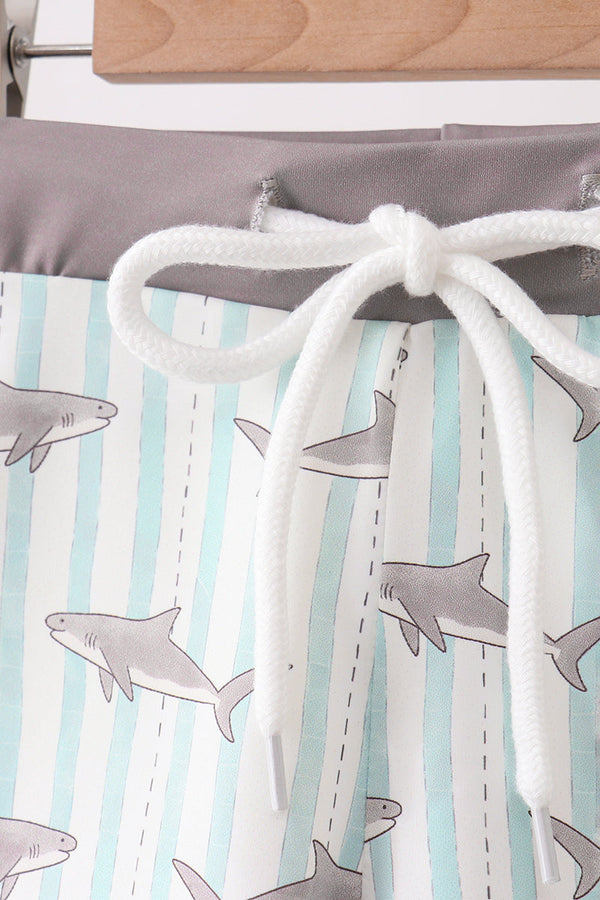 Children's shorts with shark pattern and white drawstring on a striped background