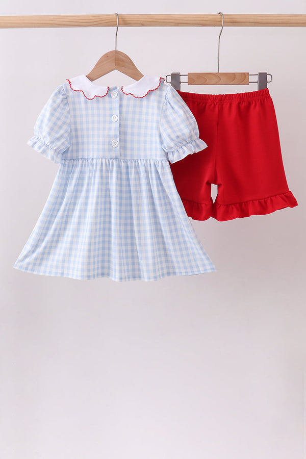 Light blue gingham dress with puff sleeves and white collar, paired with red shorts with a ruffle hem.