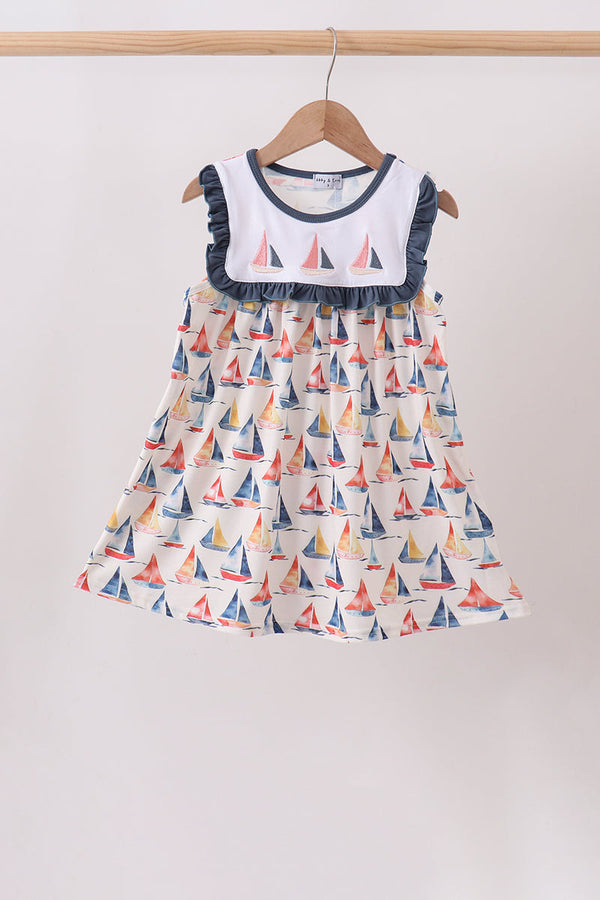 Children's dress with sailboat pattern on a hanger against a white background