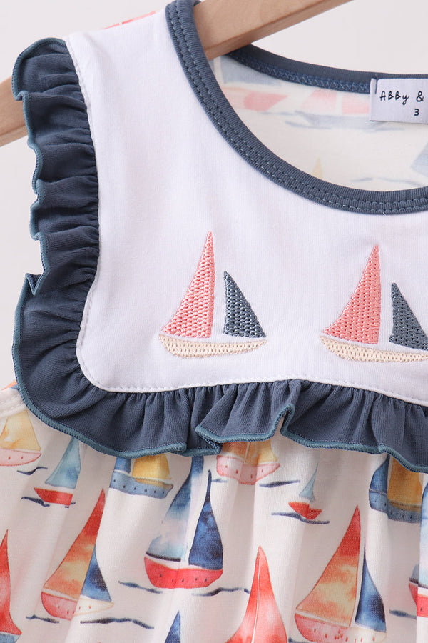Children's dress with sailboat pattern and ruffled collar on a hanger