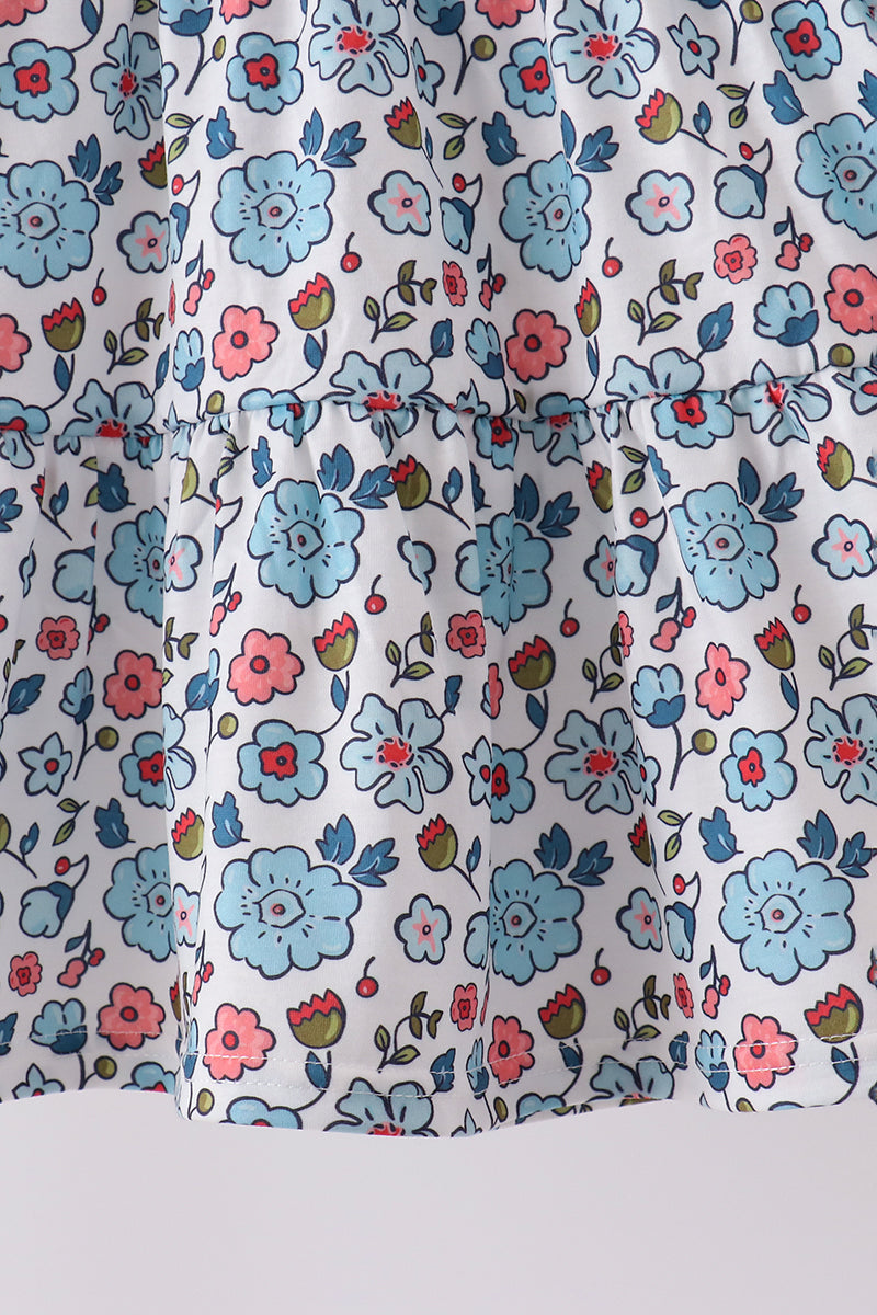Blue floral girls dress featuring delicate smocked bodice detail and a soft, romantic ruffled hemline for elegant comfort.