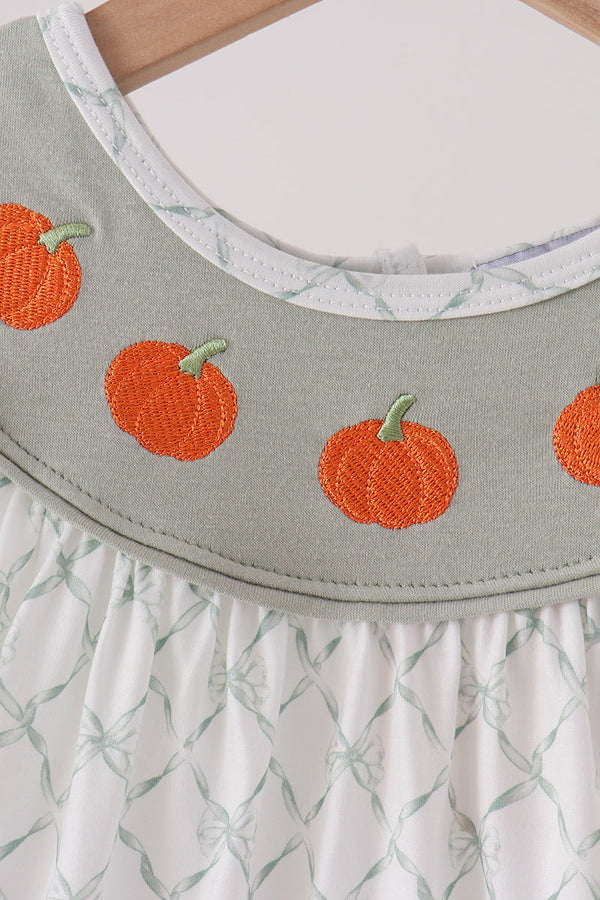 Sage green dress bodice featuring orange pumpkin embroidery and white bow pattern ruffle skirt.