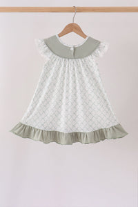 Sage green children's dress with ruffled collar, lattice print, and sage ruffle hem hanging on a wooden hanger.
