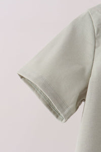 Sage green short sleeve fabric detail with visible stitching from the embroidered pumpkin shorts set.