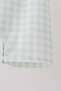 Sage green gingham fabric detail from a baby romper featuring snap closure and classic check pattern for autumn wear.