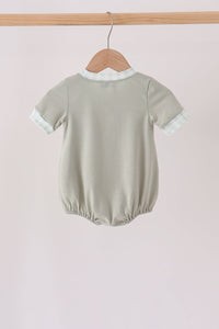 Back view of sage green bubble romper with gingham collar and cuffs hanging on a wooden hanger.