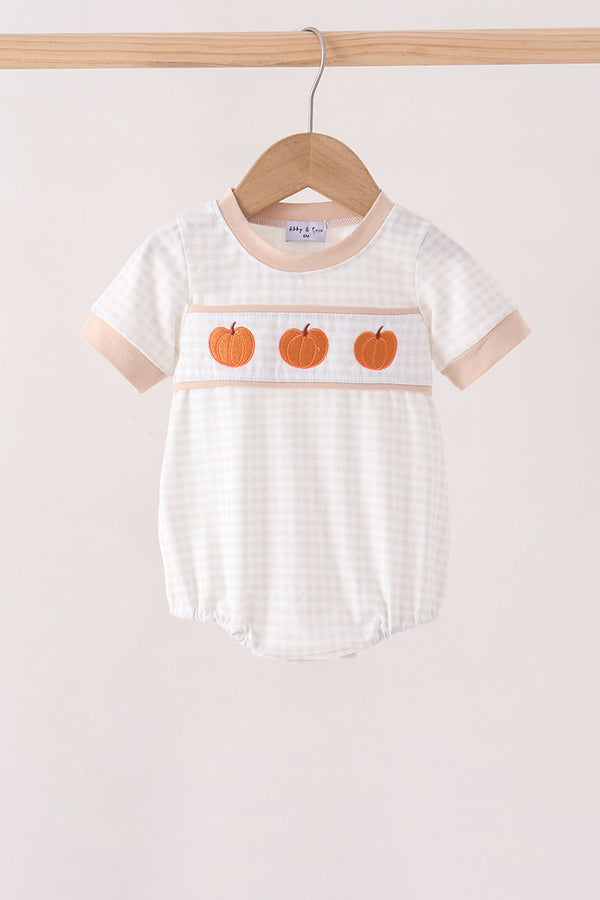 White gingham baby bubble with peach trim and three orange pumpkin embroidery patches, hanging on a wooden hanger for autumn.