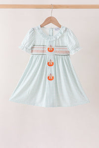 Sage pumpkin smocked gingham dress with ruffled neckline, short puff sleeves, and three embroidered orange pumpkins down the front.