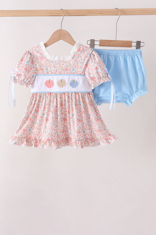 Pink floral baby dress with embroidered pumpkins paired with light blue bloomers on a hanger.