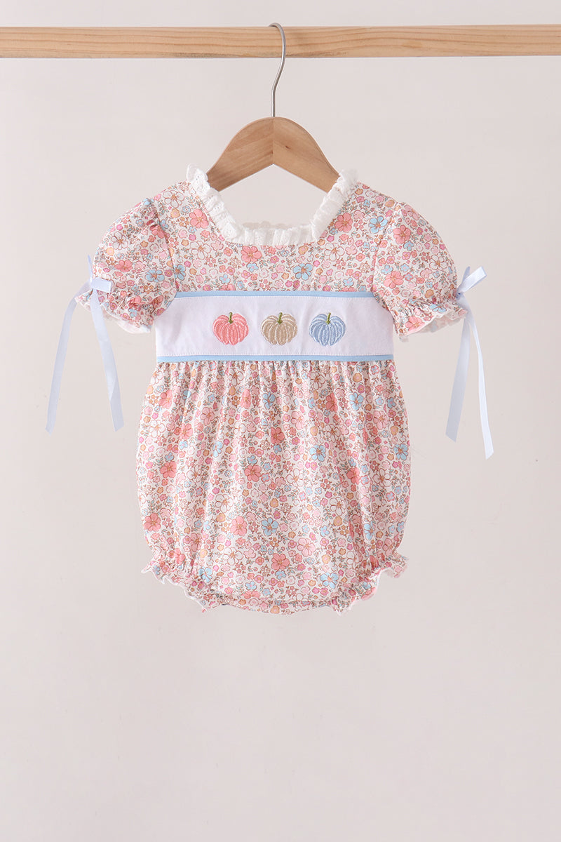 Floral print baby bubble outfit with embroidered pink, beige, and blue pumpkins on white chest band and ribbon tie sleeves.