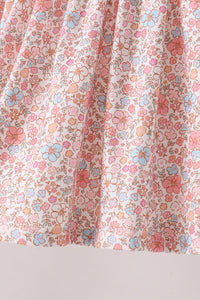 Pink floral fabric detail with folded pleats featuring blue, pink, and orange flowers on a light background for an autumn shorts set.
