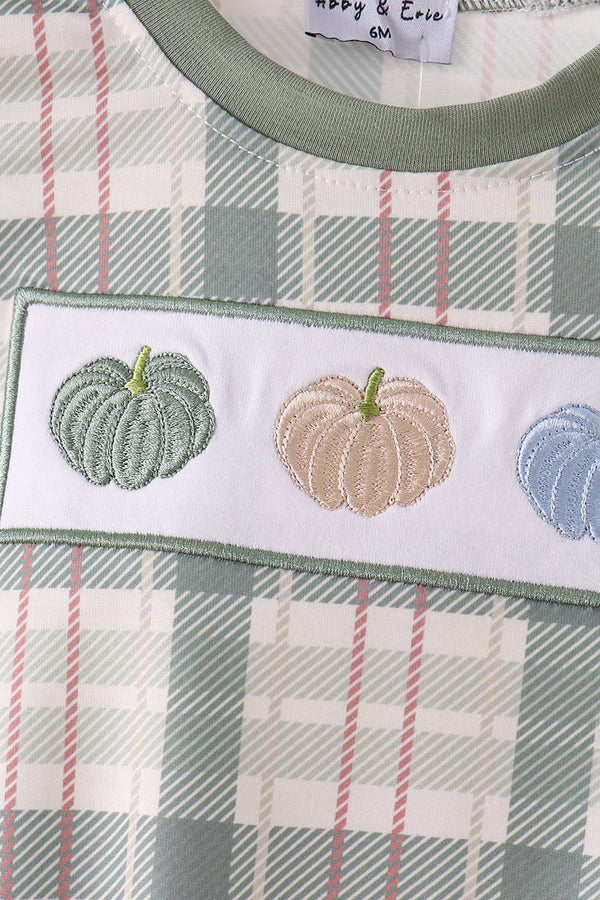 Green pumpkin embroidery on plaid fabric detail of a cozy baby bubble gown with festive fall charm.