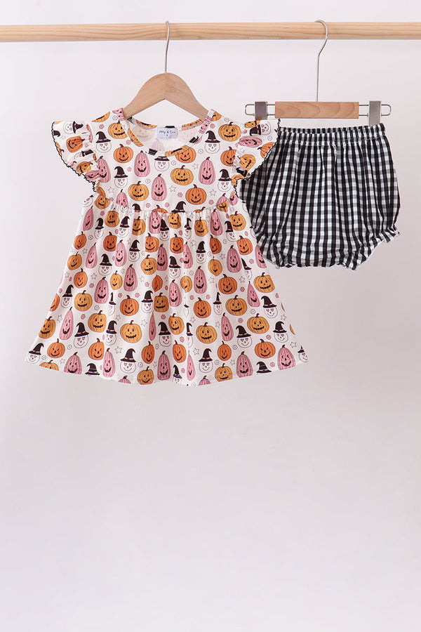 A toddler girl's two-piece Halloween outfit hanging on wooden hangers against a plain light background. The set includes a short-sleeve dress with an all-over pumpkin print and matching black-and-white gingham bloomers.