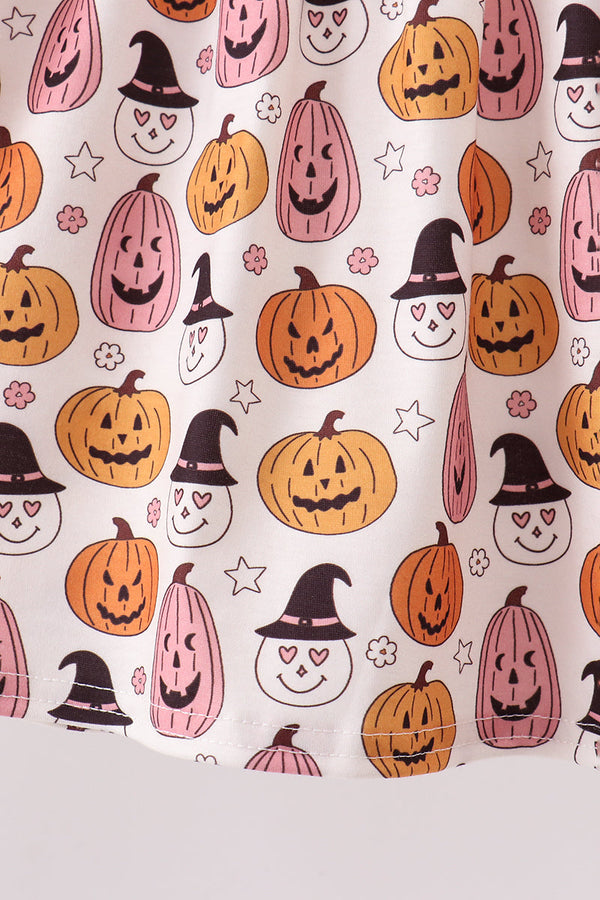 A close-up of a white fabric with a repeating Halloween pattern featuring orange jack-o'-lanterns, pink witch hats, and black outlines on a light gray background.