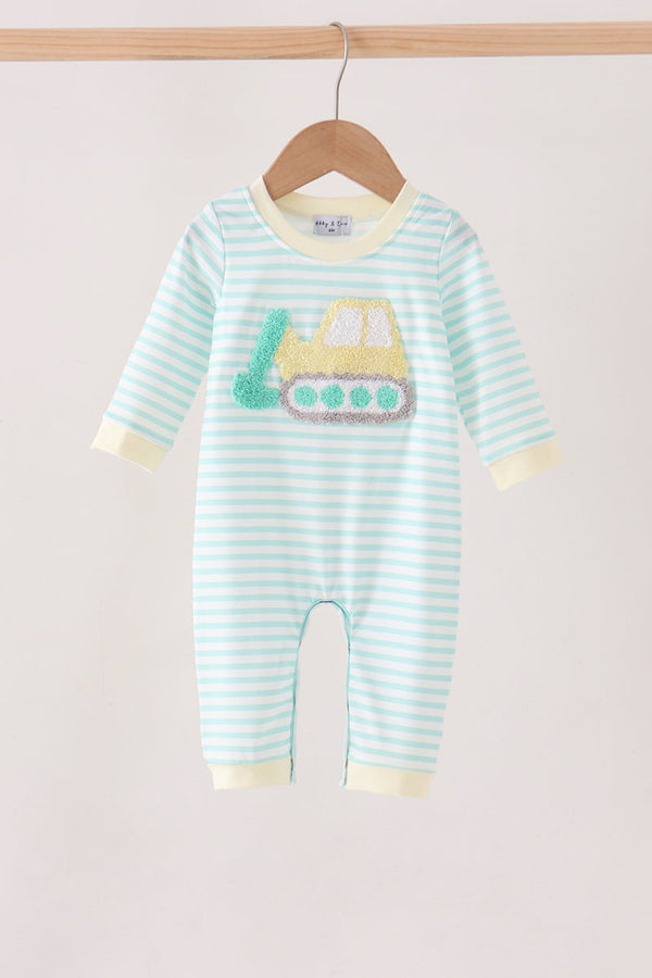 A baby long-sleeve footless romper with light blue and white horizontal stripes, featuring a yellow construction truck applique on the chest, hanging on a wooden hanger against a light beige background.