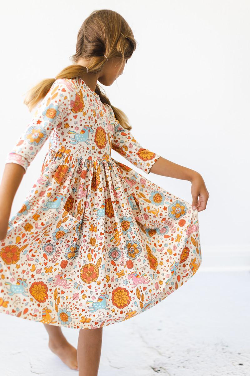 Girl twirling in the Retro Unicorns 3/4 Sleeve Pocket Twirl Dress for girls, showcasing the vibrant floral pattern and the dress's twirl-friendly design.